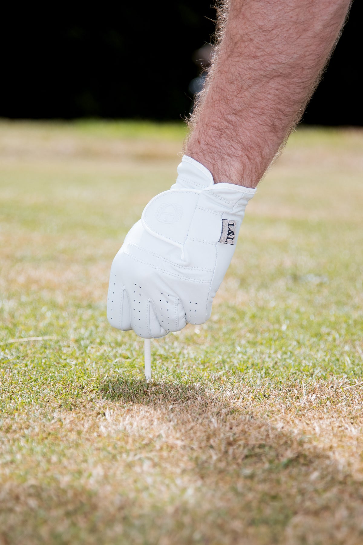 Close detail of a white Links And Leather golf glove being worn